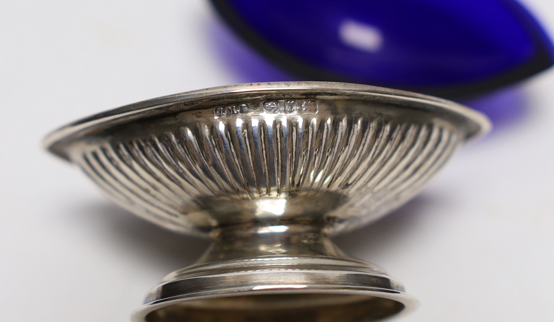 A set of four Victorian elliptical shaped silver pedestal salts, Birmingham, 1891, 58mm, with blue glass liners and a set of four silver plated salts.